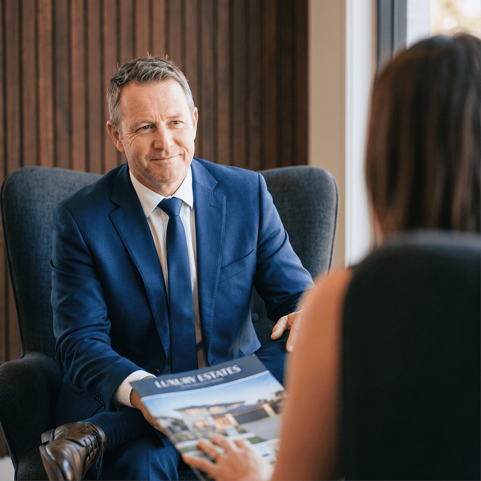 A Blue Ribbon agent presenting a property brochure to a client